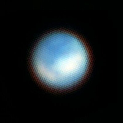 A blue-and-white sphere against a black background is somewhat reminiscent of the famous “Blue Marble” picture of Earth from space. With fuzzy, diffuse edges, this sphere features darker blue patches in most of the northern hemisphere facing the viewer.
